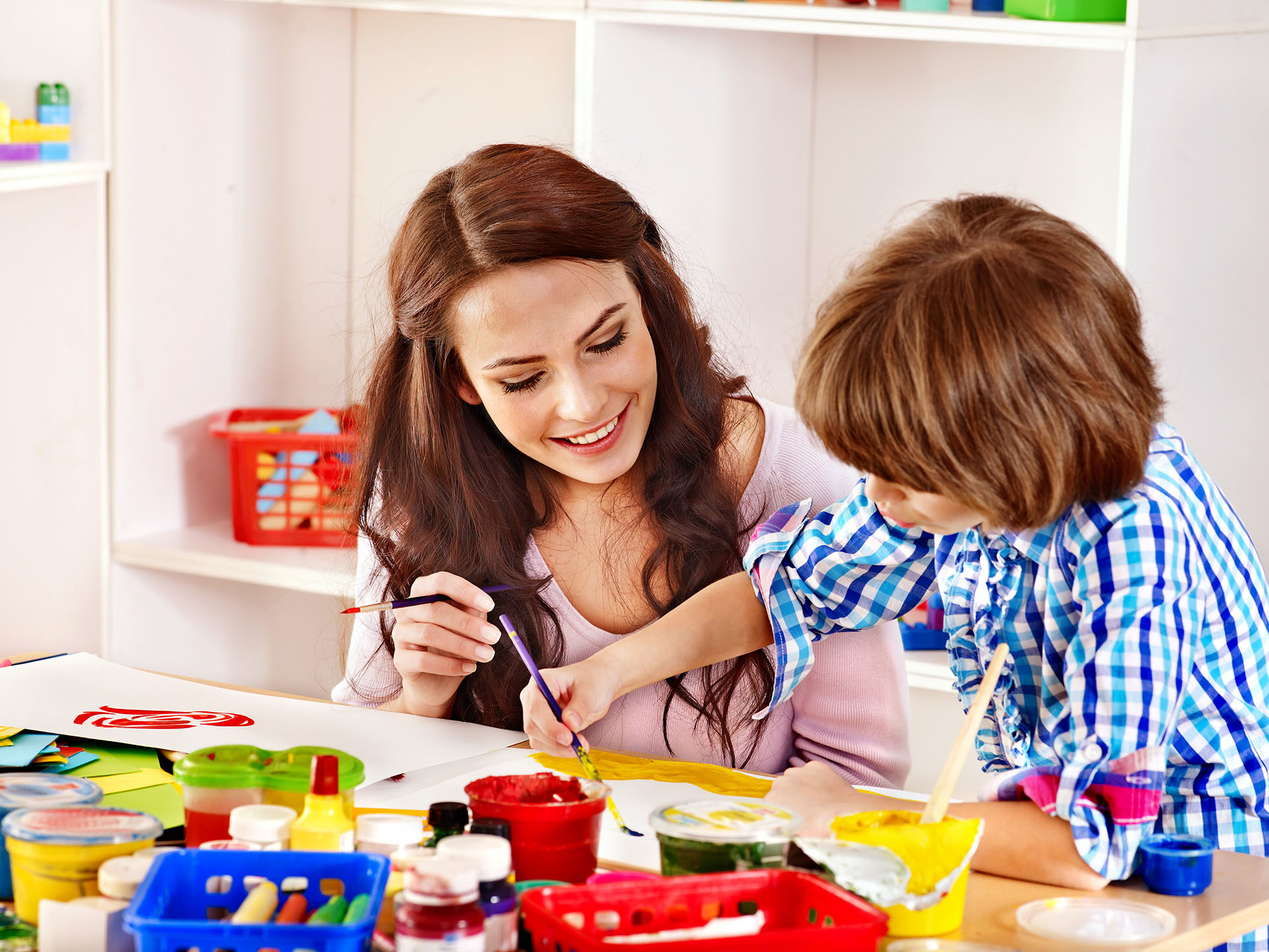 childcarer and boy painting