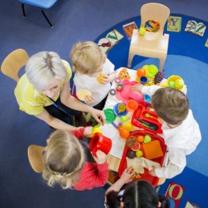 children playing with childcare worker in nursery