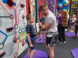Climbing instructor helps a small boy in Clip 'n Climb at High Rise Lisburn